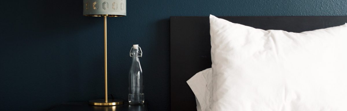 Image of a bed lamp illuminating a water bottle on a nightstand