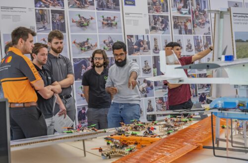 A group of students point at an engineering project